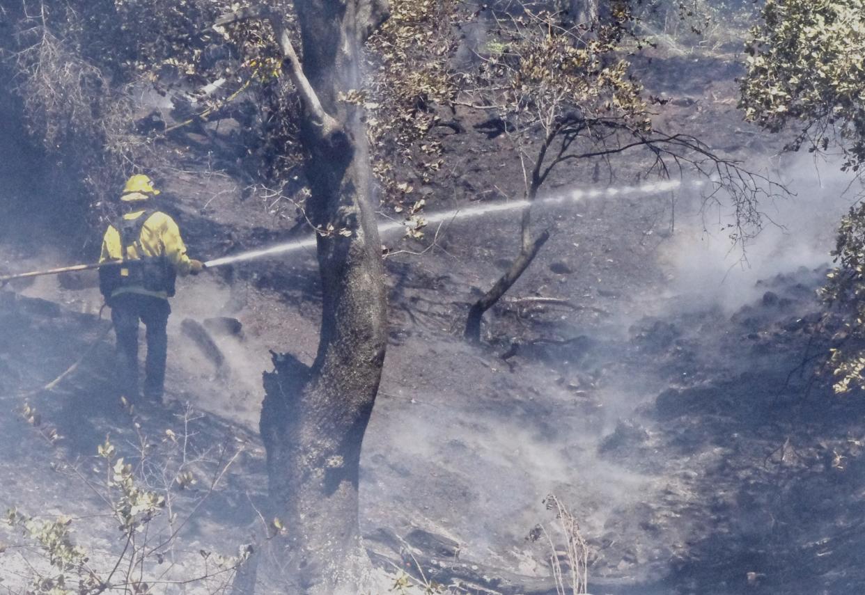 A Redding Fire Department firefighters hoses down a fire off Barbara Road just north of Benton Drive in Redding on Friday, June 23, 2023.