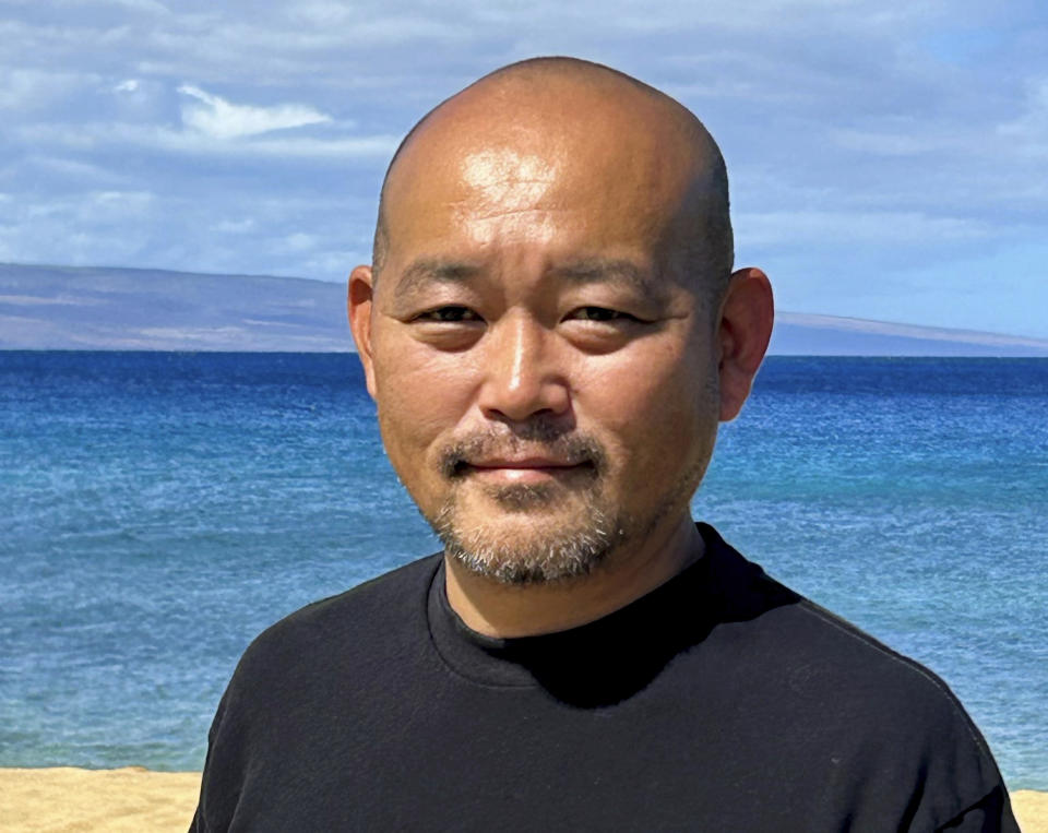 In this photo provided by the Rev. Ai Hironaka, he takes a photo of himself on a beach in Lahaina, Hawaii, on Thursday, Sept. 21, 2023. Hironaka and other Lahaina residents are grappling with a range of emotions about returning to the ruins of Lahaina after a deadly August 2023 wildfire. (Ai Hironaka via AP)