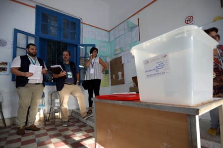 Electoral workers and inspectors are seen inside a polling station during presidential election in Tunis