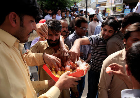 Supporters of the opposition Tehreek-e-Insaf (PTI) party distribute sweets to celebrate disqualification of Foreign Minister Khawaja Asif from parliament, outside the Islamabad High Court in Islamabad, Pakistan April 26, 2018. REUTERS/Faisal Mahmood