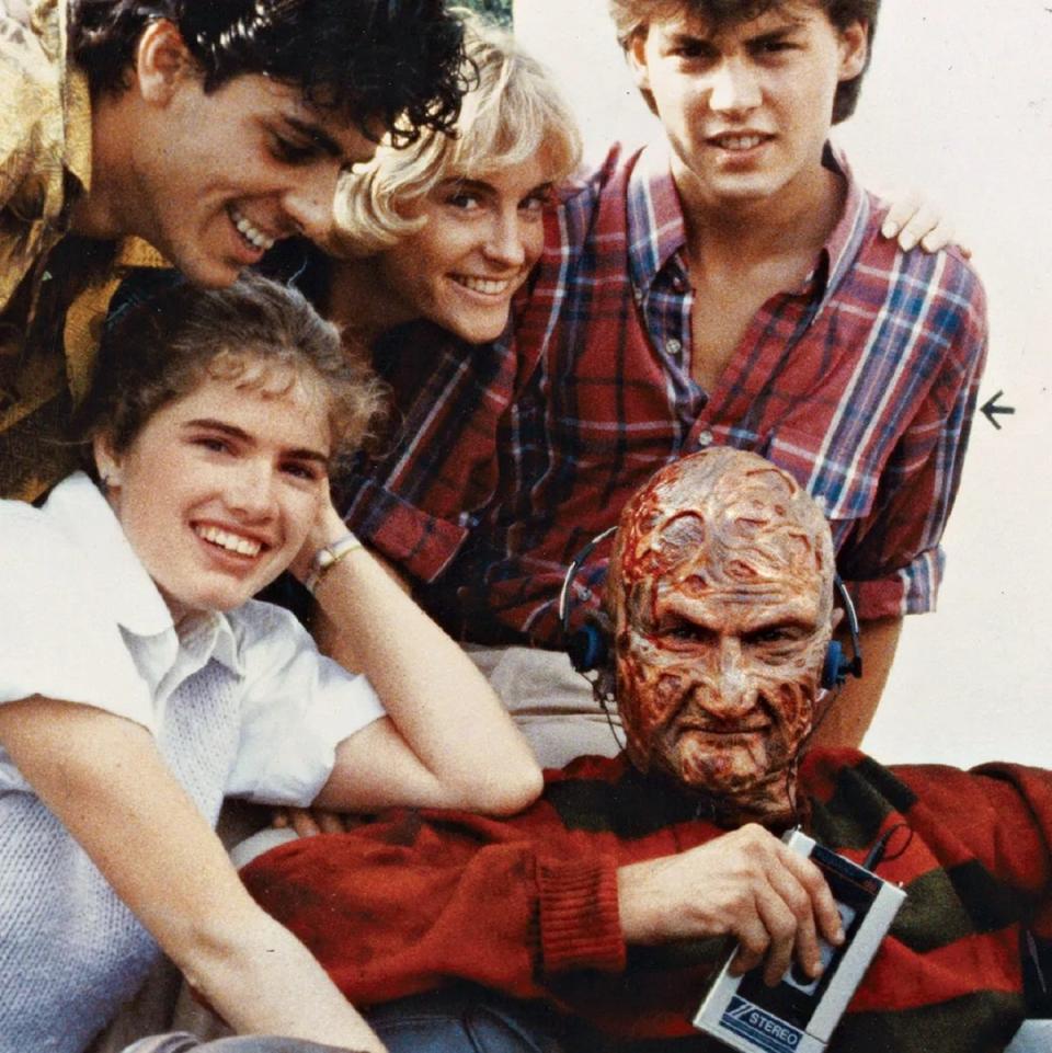Robert Englund in Freddy Krueger makeup on the set of the original A Nightmare on Elm Street, along with the young cast.