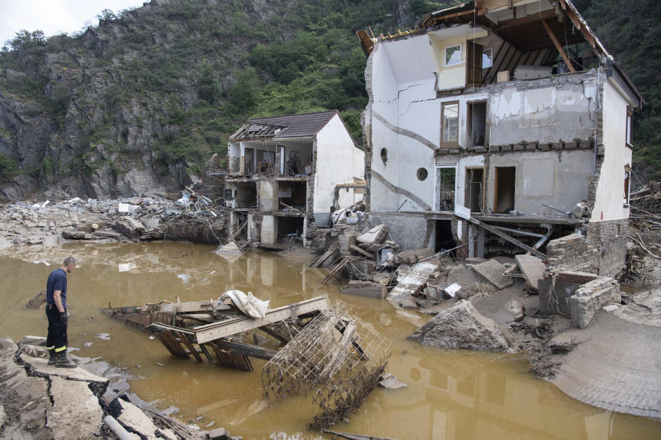 A fireman stands in front of a completely destroyed house in the village of Mayschoß, Germany, Tuesday, July 20, 2021. Numerous houses in the village were badly affected or completely swept away by the flood wave. (Boris Roessler/dpa via AP)