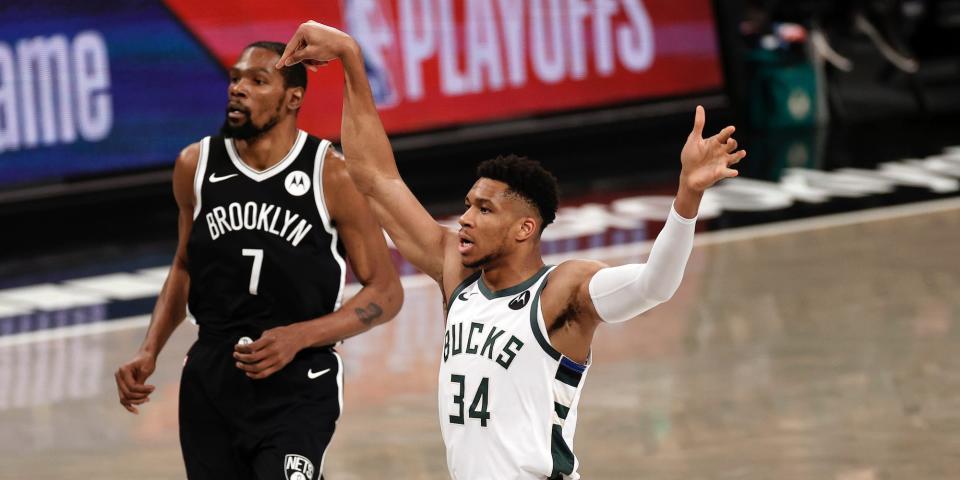 Kevin Durant looks on as Giannis Antetokounmpo holds his follow-through after a shot.