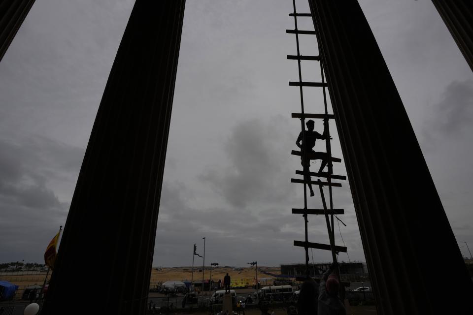 A protester uses an improvised ladder as he prepares to leave the premise in Colombo, Sri Lanka, Thursday, July 21, 2022. (AP Photo/Eranga Jayawardena)