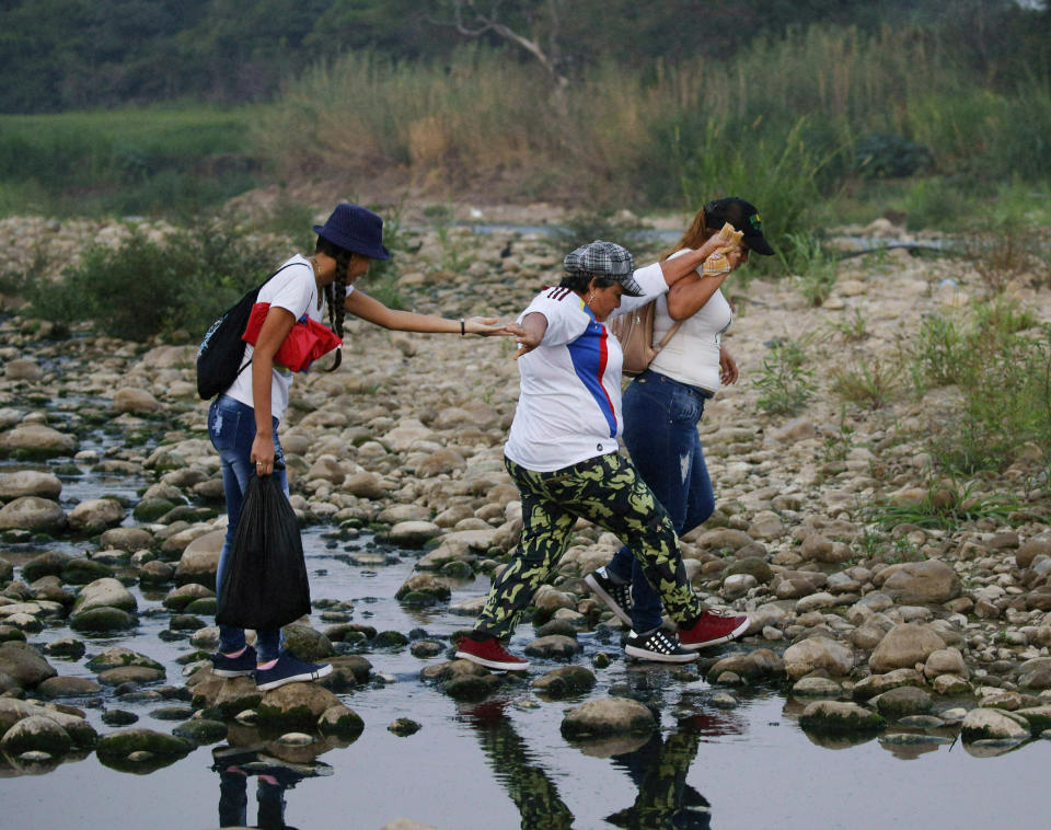 Mujeres cruzan el río Táchira en la frontera entre Venezuela y Colombia para asistir al concierto de Venezuela Aid Live en el lado colombiano de la frontera, en Palotal, Venezuela, el viernes 22 de febrero de 2019. (AP Foto/Fernando Llano)