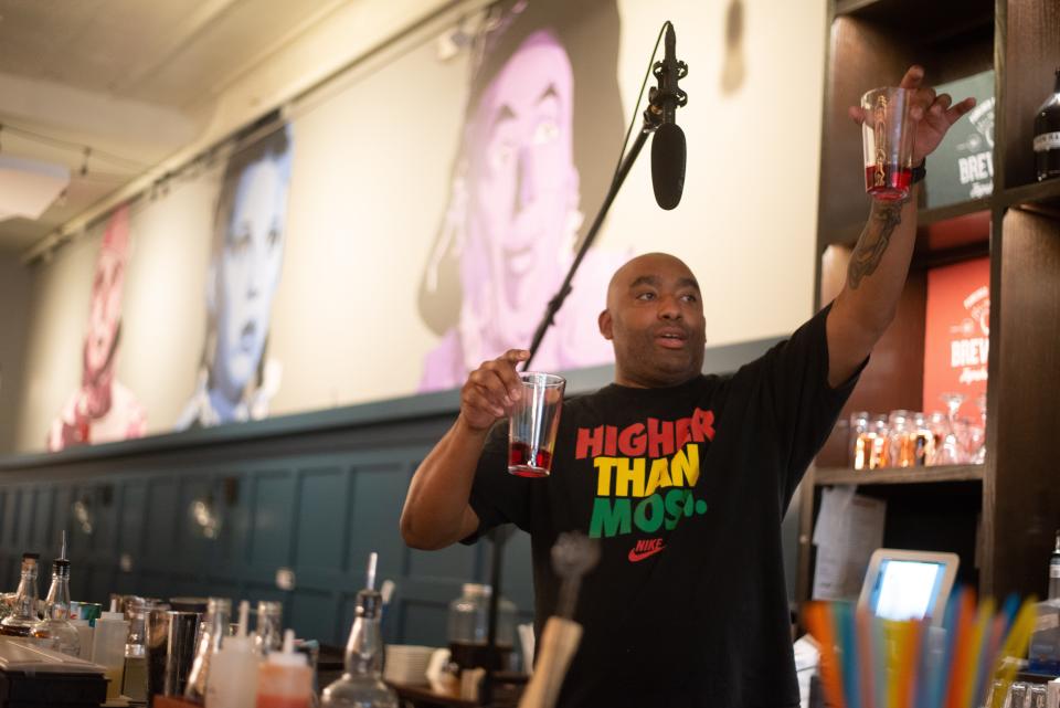 Ty Platt, a bartender at Brew Bank, holds up examples of properly portioned pours of spirits during a mixology class held last May.