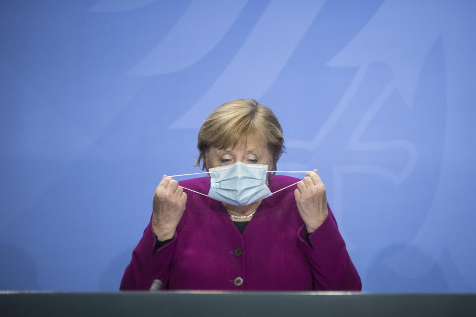 German Chancellor Angela Merkel holds her face mask as she arrives for a press conference after a meeting with the governors of the German states in Berlin Germany, Wednesday, Oct. 14, 2020. (Stefanie Loos/Pool Photo via AP)