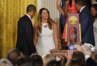 UConn women's basketball star Stefanie Dolson (C) curtsies as she stands between U.S. President Barack Obama (L) and UConn women's head basketball coach Geno Auriemma (R) after Dolson fell off the side of the stage during a ceremony honoring the NCAA basketball champion University of Connecticut Huskies men's and women's basketball teams in the East Room of the White House in Washington, June 9, 2014. Dolson was uninjured in the fall. REUTERS/Jim Bourg (UNITED STATES - Tags: POLITICS SPORT BASKETBALL)