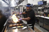 A cook prepares a meal at Slater's 50/50 Wednesday, July 1, 2020, in Santa Clarita, Calif. California Gov. Gavin Newsom has ordered a three-week closure of bars, indoor dining and indoor operations of several other types of businesses in various counties, including Los Angeles, as the state deals with increasing coronavirus cases and hospitalizations. (AP Photo/Marcio Jose Sanchez)