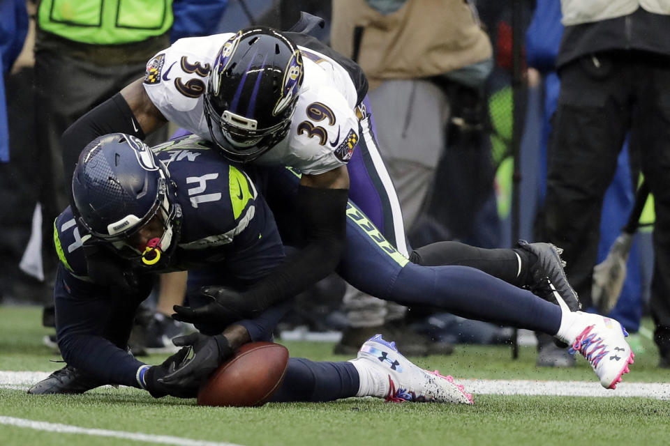 Seattle Seahawks wide receiver D.K. Metcalf (14) fumbles as he is hit by Baltimore Ravens cornerback Brandon Carr (39) during the second half of an NFL football game, Sunday, Oct. 20, 2019, in Seattle. Ravens' Marlon Humphrey recovered the fumble and ran for a touchdown. (AP Photo/John Froschauer)