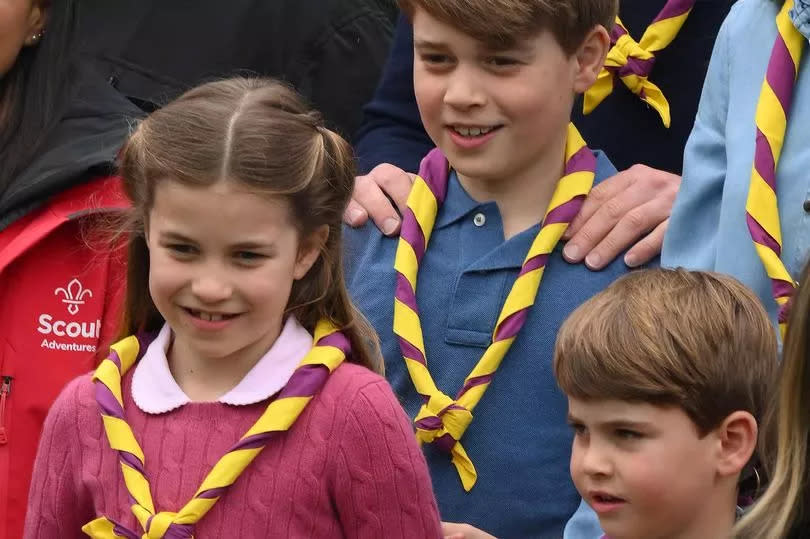 Britain's Prince George of Wales (C), Britain's Prince Louis of Wales (R) and Britain's Princess Charlotte of Wales (L) pose for a group picture with volunteers who are taking part in the Big Help Out, during a visit to the 3rd Upton Scouts Hut in Slough, west of London on May 8, 2023, where the family helped to renovate and improve the building.