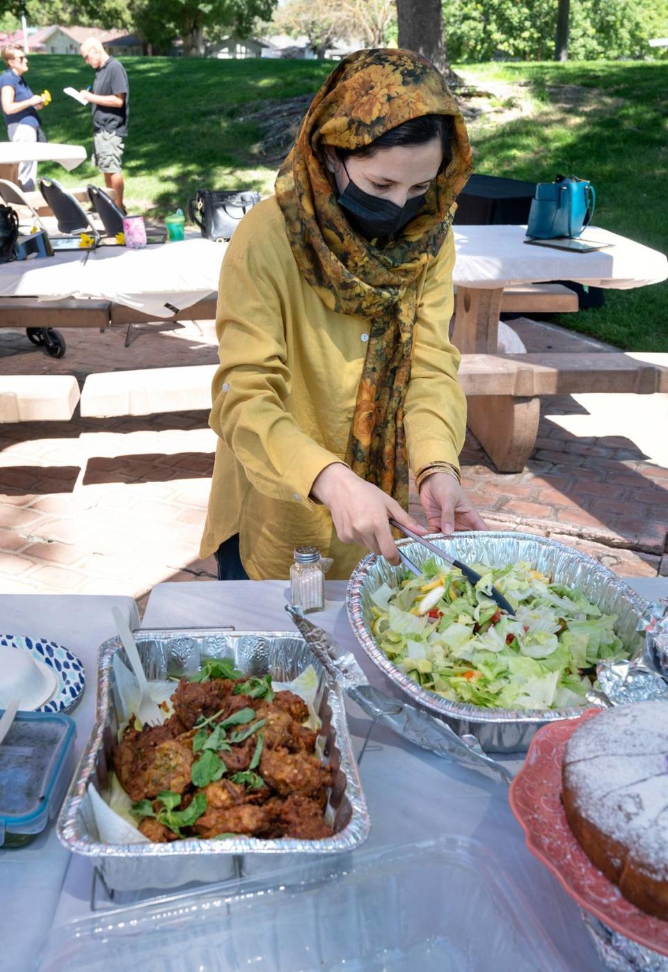 Estori Afzali serves up some traditional Afghan food during a potluck lunch after a graduation ceremony at Davis Park in Modesto Calif., on Friday, July 1, 2022. Seventeen women refugees from Afghanistan are the first graduates of the International Rescue Committee and Modesto Junior College’s child care microenterprise development program for home child-care licensing.