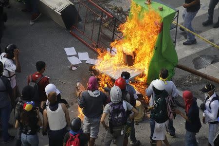 Demonstrators watch a barricade burn after clashes broke out while the Constituent Assembly election is being carried out in Caracas, Venezuela, July 30, 2017. REUTERS/Carlos Garcia Rawlins