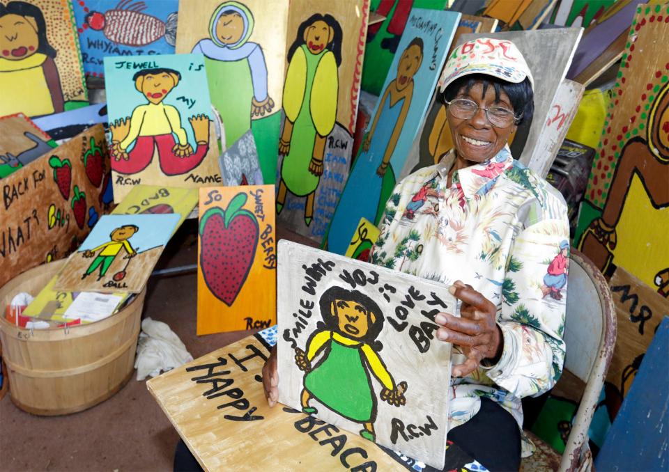Folk artist Ruby C. Williams sits among her paintings at her fruit and vegetable stand along SR 60 in Bealsville.