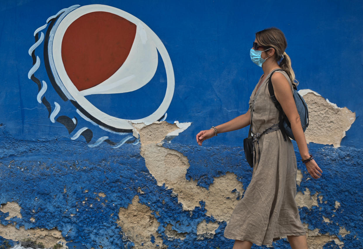 A woman wearing a face mask walks past a Pepsi ad in Mexico on February 13, 2022. (Photo by Artur Widak/NurPhoto via Getty Images)