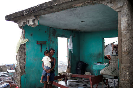 Nathalie Pierre, 28, poses for a photograph with her daughter Rose, 3, in their destroyed house after Hurricane Matthew hit Jeremie, Haiti, October 17, 2016. "As you can see, my situation is very bad. I lost all I had; my house, my money, my boutique. Everything gone in a few minutes. The storm was terrible but I was lucky to have my only daughter alive - that's the most important thing. Life goes on," said Pierre. REUTERS/Carlos Garcia Rawlins