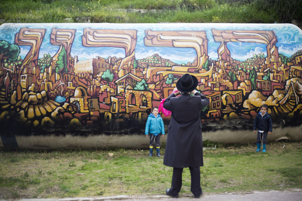 In this March 7, 2017 photo, a Jewish man takes a photo of his children in the Israeli controlled part of the West Bank city of Hebron. The Falic family, owners of the ubiquitous chain of Duty Free America shops, fund a generous, and sometimes controversial, philanthropic empire in Israel that stretches deep into the West Bank. The family supports many mainstream causes as well as far right causes considered extreme even in Israel. (AP Photo/Ariel Schalit)