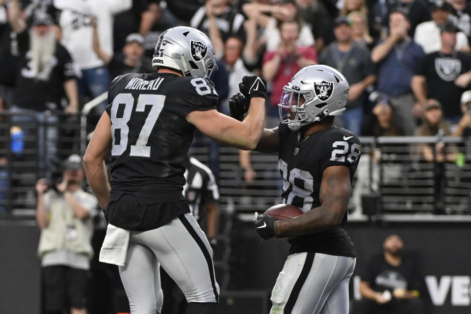 Las Vegas Raiders running back Josh Jacobs (28) celebrates his touchdown with tight end Foster Moreau (87) during the first half of an NFL football game against the Los Angeles Chargers, Sunday, Dec. 4, 2022, in Las Vegas. (AP Photo/David Becker)