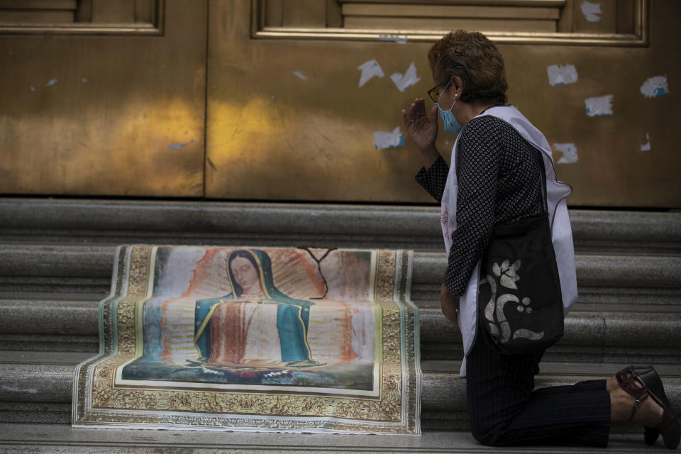 An activist against abortion makes the sign of the cross as she places an image of Our Lady of Guadalupe at the entrance to the Supreme Court to celebrate the court's decision against an injunction in Veracruz state that aimed to decriminalize abortion for all cases within the first 12 weeks of pregnancy, in Mexico City, Wednesday, July 29, 2020. Two of Mexico’s 32 states have decriminalized abortion. (AP Photo/Fernando Llano)