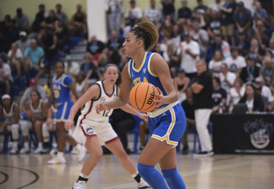 UCLA's Kiki Rice brings the ball up the floor as UConn's Ashlynn Shade watches during the second half of an NCAA college basketball game at the Cayman Islands Classic in George Town, Cayman Islands, Friday, Nov. 24, 2023. (AP Photo/Kevin Morales)