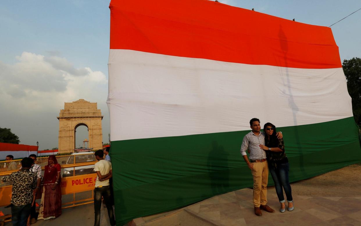 A couple pose in front of a flag at the India Gate on the eve of Independence Day celebrations in New Delhi - REUTERS