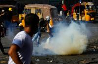 Iraqi demonstrators run away from tear gas thrown by Iraqi security forces during ongoing anti-government protests in Baghdad