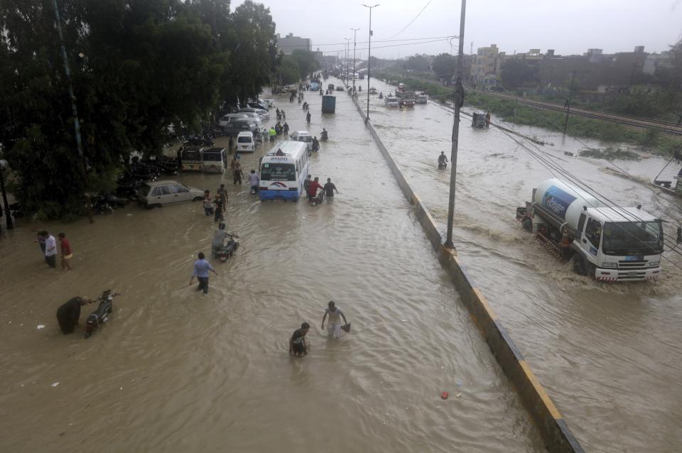 People wade through a flooded road after heavy monsoon rains, in Karachi, Pakistan, Thursday, Aug. 27, 2020. Heavy monsoon rains have lashed many parts of Pakistan as well the southern port city of Karachi, leaving flooding streets, damaging homes and displacing scores of people. (AP Photo/Fareed Khan)