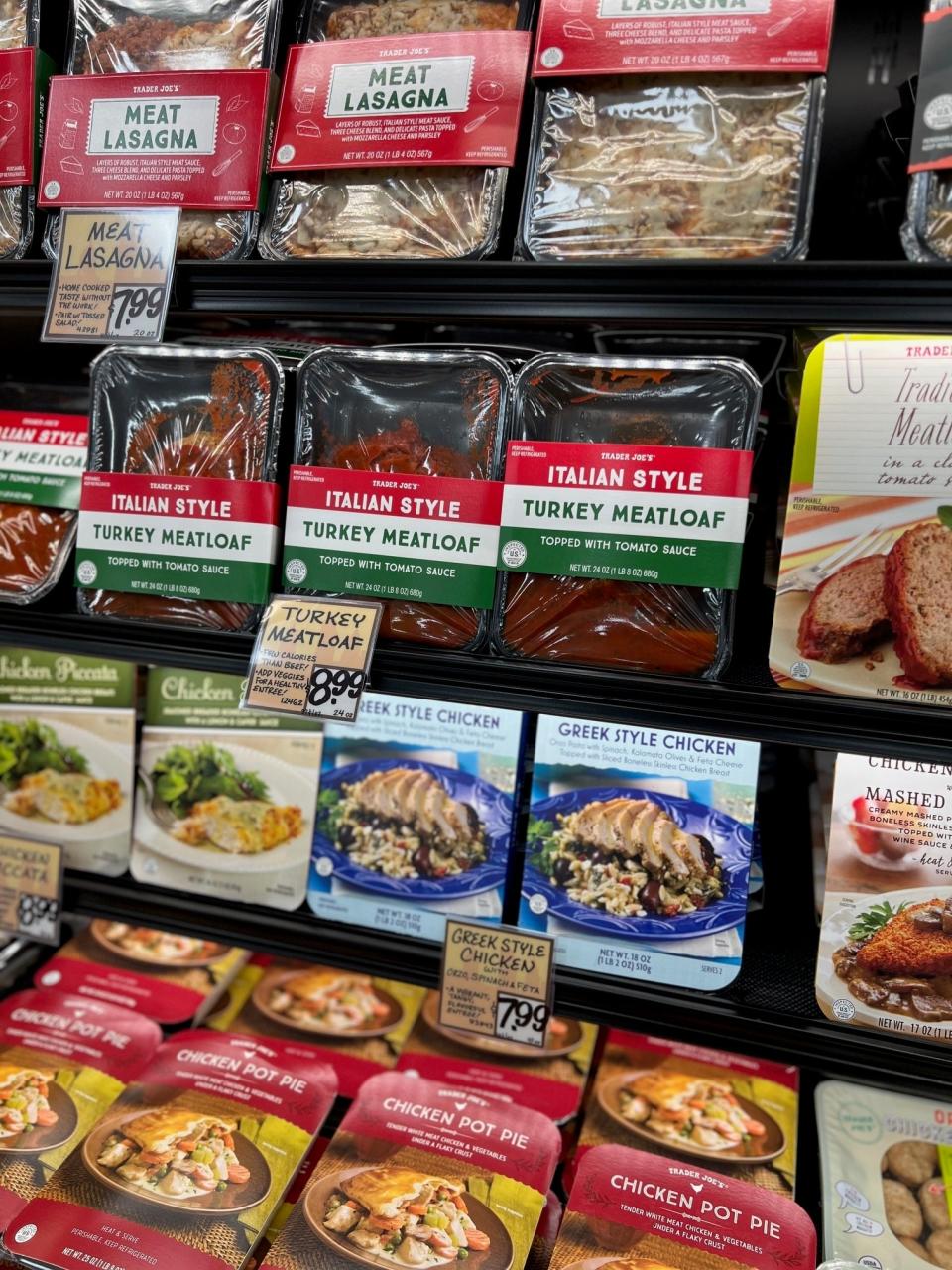 Ready-to-eat meal packages displayed on a grocery store shelf, including Italian style turkey meatloaf and Greek style chicken