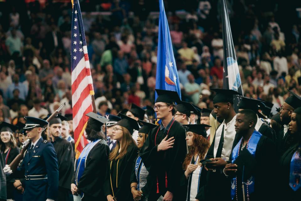 Graduates put their hands over their hearts during the national anthem during the commencement ceremony for University of Memphis graduates on Saturday, May 04, 2024, at the FedEx Forum in Downtown Memphis.