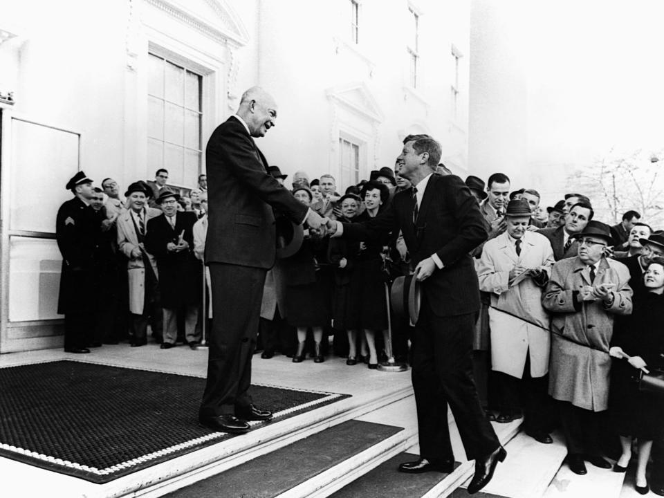President Dwight Eisenhower welcomes then President-elect John F. Kennedy to the White House with a handshake in 1960.