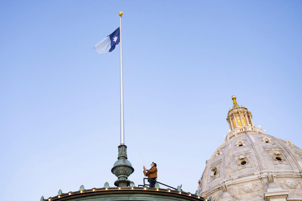 Charlie Krueger, a grounds supervisor for facilities management at the Department of Administration, raises the new Minnesota state flag for the first time at sunrise atop the Minnesota State Capitol in St. Paul, Minn., on Saturday, May 11, 2024. Minnesota officially unfurled its new state flag atop the capitol for the first time Saturday on statehood day. (Alex Kormann/Star Tribune via AP)