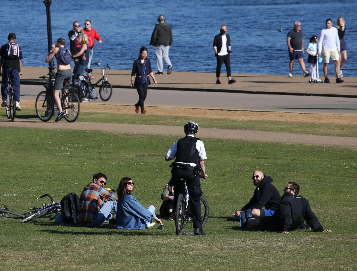 A police officer speaks to people relaxing by the Serpentine in Hyde Park, London, as the UK continues in lockdown to help curb the spread of the coronavirus.