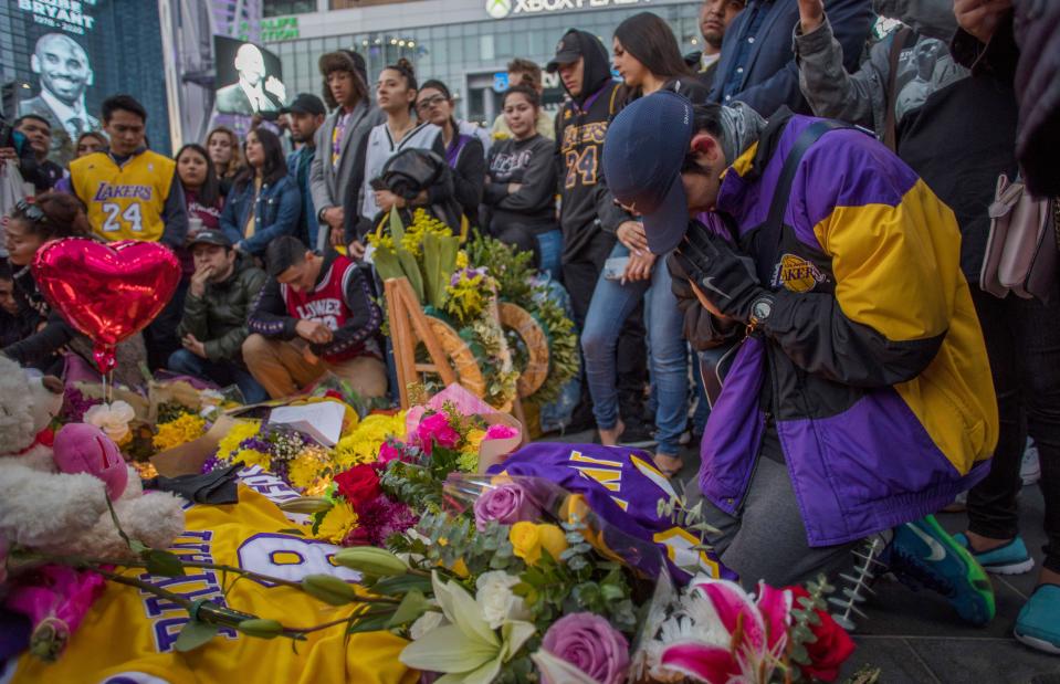People gather around a makeshift memorial for former NBA and Los Angeles Lakers player Kobe Bryant after learning of his death, at LA Live plaza in front of Staples Center in Los Angeles on January 26, 2020. - Nine people were killed in the helicopter crash which claimed the life of NBA star Kobe Bryant and his 13 year old daughter, Los Angeles officials confirmed on Sunday. Los Angeles County Sheriff Alex Villanueva said eight passengers and the pilot of the aircraft died in the accident. The helicopter crashed in foggy weather in the Los Angeles suburb of Calabasas. Authorities said firefighters received a call shortly at 9:47 am about the crash, which caused a brush fire on a hillside. (Photo by Apu GOMES / AFP) (Photo by APU GOMES/AFP via Getty Images)