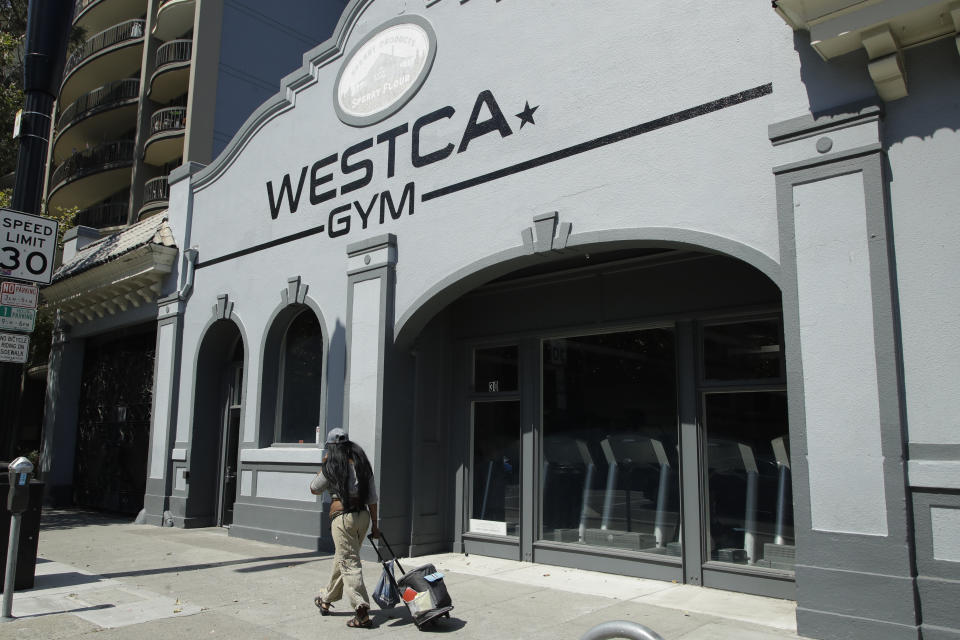 A person walks past the closed Westca Gym on Monday, July 6, 2020, in San Jose, Calif. The Independence Day weekend saw one of Santa Clara County's largest increases in COVID-19 cases to date, which came as the state of California denied the county's application for further reopening of businesses and activities. (AP Photo/Ben Margot)