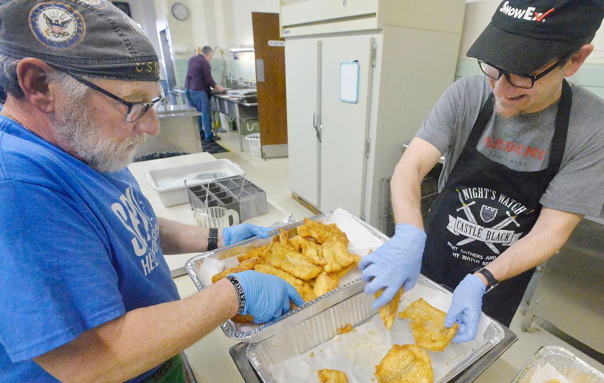 John Villa, 64, left, and Rick Linker, 52, replenish fish on the take-out line during a Lenten fish dinner on March 4 at St. Stanislaus Catholic Church in Erie. Villa has been volunteering for many years while Linker, visiting from Richmond, Va., with his wife Kate, an Erie native, is working the dinner for the first time.