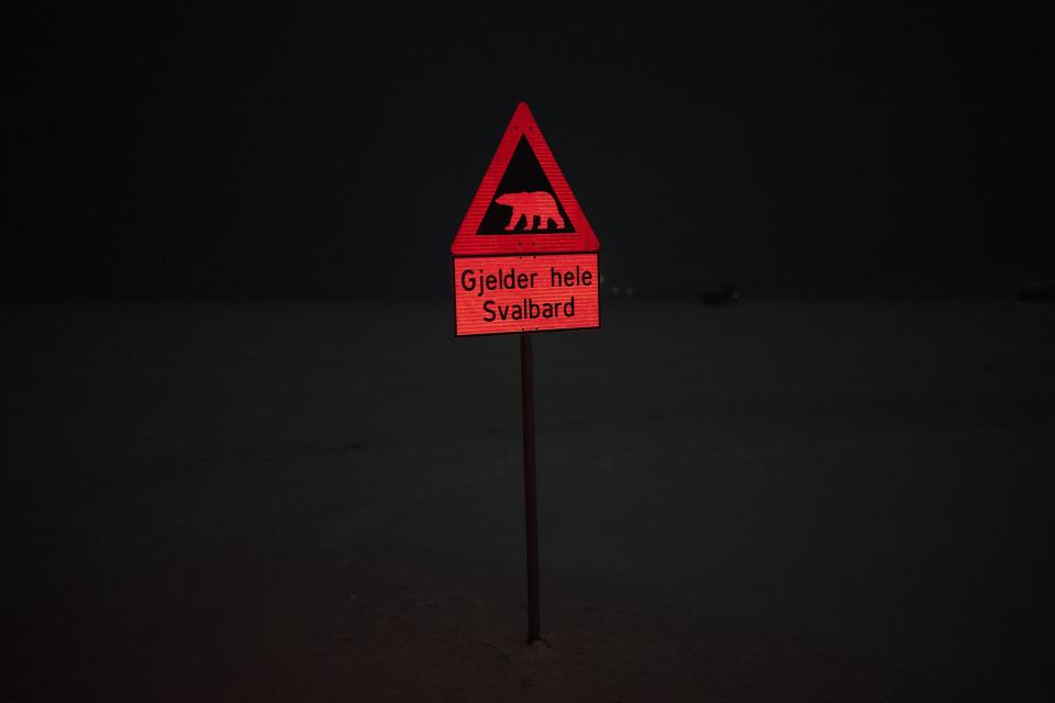 A sign signals the danger of polar bears at the edge of Longyearbyen, Norway, Monday, Jan. 9, 2023. To go anywhere beyond the limits of Longyearbyen, people are advised to have protection, like a flare gun and firearm, a warning that locals take very seriously. (AP Photo/Daniel Cole)