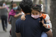 People carry their child wearing face masks to help curb the spread of the coronavirus head to a kindergarten in Beijing on June 9, 2021. If China is to meet its tentative goal of vaccinating 80% of its population against the coronavirus by the end of the year, tens of millions of children may have to start rolling up their sleeves. (AP Photo/Andy Wong)