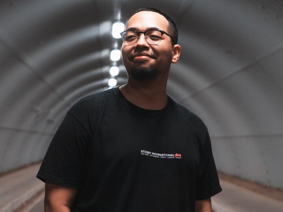 Man in a brightly lit tunnel wearing glasses and a black T-Shirt