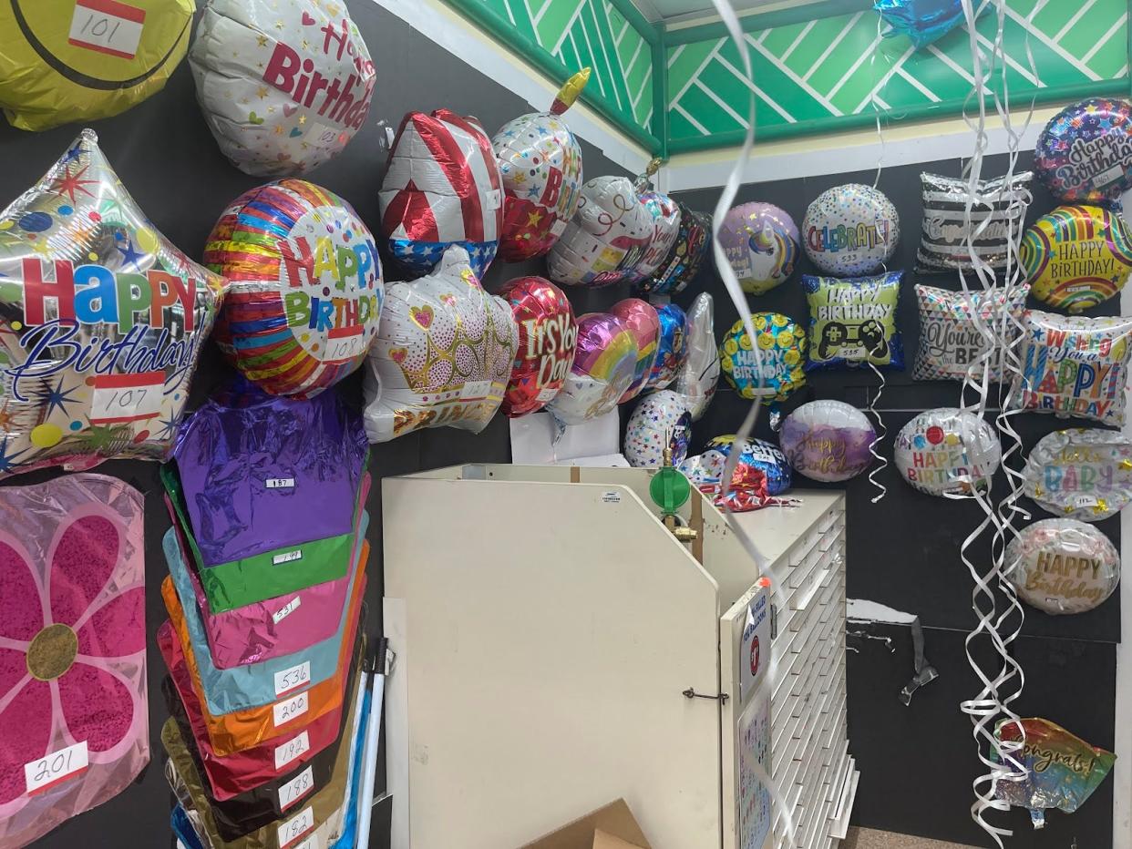 Different helium balloons on display on a wall in a store.