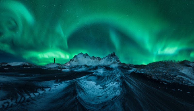A person silhouetted under the Northern Lights.