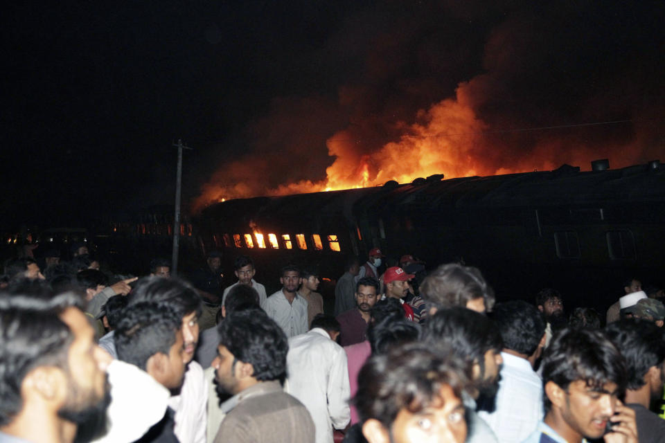 People look at a burning passenger train in Shaikhupura, near Lahore, Pakistan, early Tuesday, March 28, 2017. Authorities in Pakistan say a passenger train has collided with an oil tanker truck, killing at least one person and injuring others. (AP Photo/K.M. Chaudary)