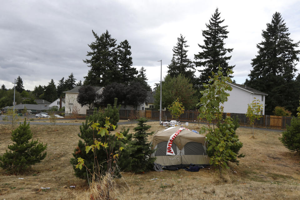 FILE - In this Sept. 19, 2017, file photo, a tent and trash are shown near a neighborhood of other homes in Portland, Ore. Voters in metropolitan Portland will be asked Tuesday, May 19, 2020 to approve taxes on personal income and business profits that would raise $2.5 billion over a decade to fight homelessness even as Oregon grapples with the coronavirus pandemic and its worst recession in decades. (AP Photo/Ted S. Warren, File)