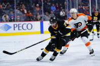 Boston Bruins' Connor Clifton, left, tries to keep the puck away from Philadelphia Flyers' Nicolas Aube-Kubel during the second period of an NHL hockey game, Wednesday, Oct. 20, 2021, in Philadelphia. (AP Photo/Matt Slocum)