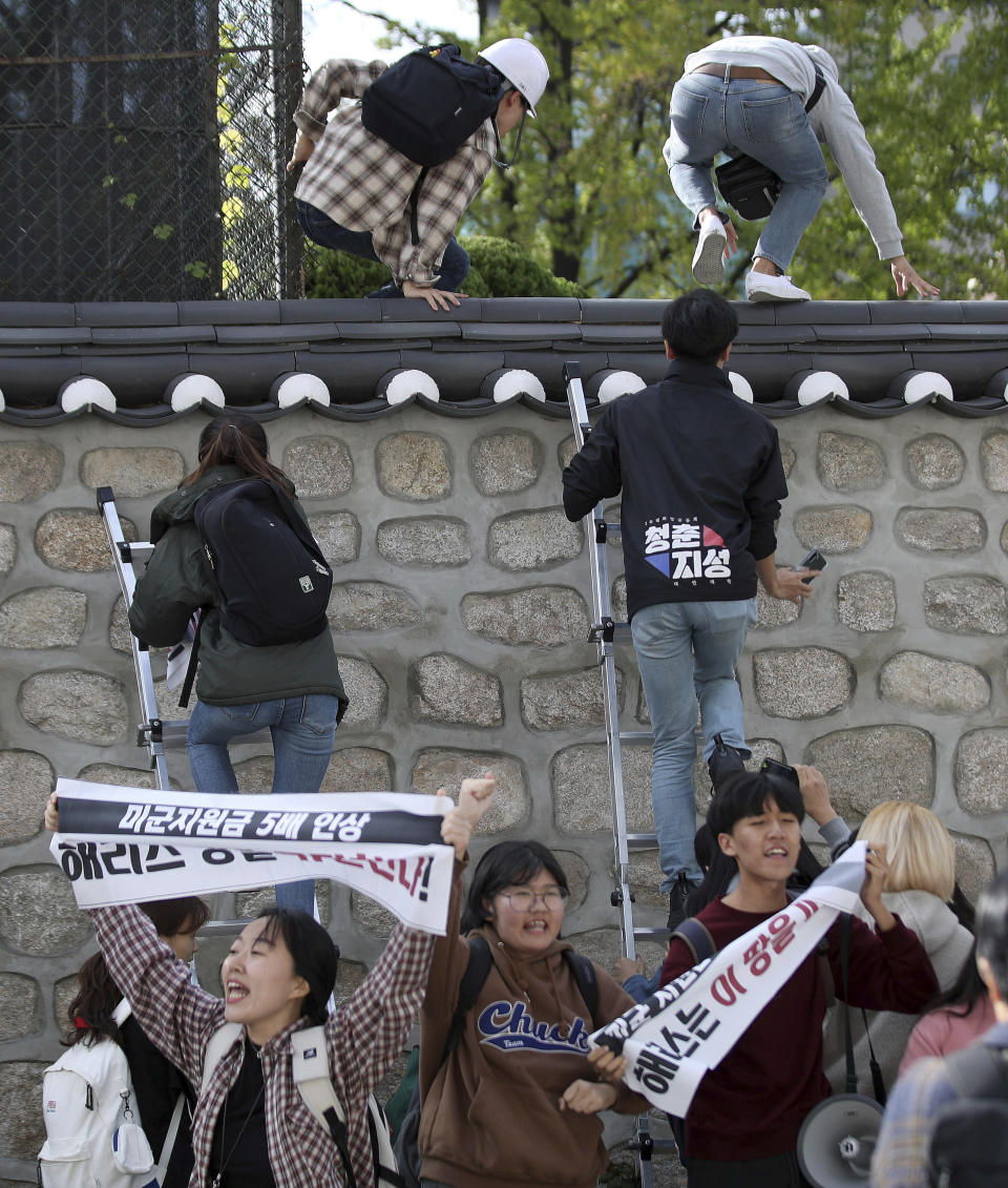 In this Friday, Oct. 18, 2019, photo, college students use ladders to climb walls of the U.S. ambassador's residence in Seoul, South Korea. South Korean police have formally on Monday, Oct. 21. arrested four anti-American students who broke into the U.S. ambassador's residence in Seoul while protesting the Trump administration's demands for South Korea to pay more to help cover the costs of keeping U.S. troops. The sign reads "Harris, leave this land!" (Kim Sun-ung/Newsis via AP)