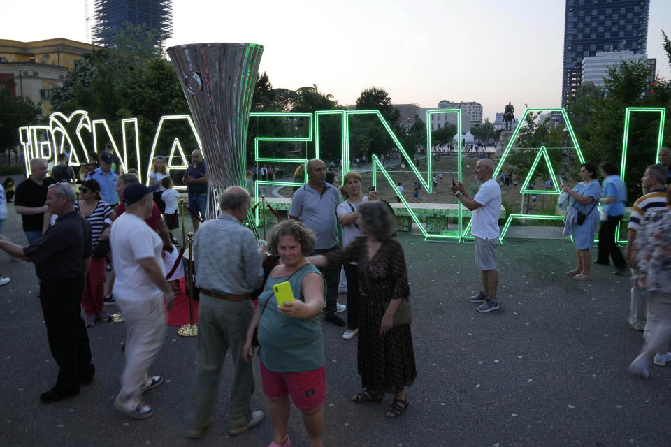 People pose for pictures next to a copy of Conference League trophy in downtown of Tirana, Albania, Tuesday, May 24, 2022. Feyenoord will play Roma Wednesday in the Europa Conference League Final. (AP Photo/Antonio Calanni)