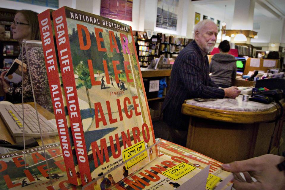 Canadian author Alice Munro's books sit on the bookshelf as her former husband Jim stands at the front counter at Munro's Bookstore in Victoria, British Columbia October 10, 2013. Munro won the Nobel Prize for her tales of the struggles, loves and tragedies of women in small-town Canada that made her what the award-giving committee called the "master of the contemporary short story." The bookstore, which celebrates its 50th anniversary this year, was opened in 1963 by Jim and Alice Munro at a smaller location nearby. The couple were divorced in 1972 and Jim continues to run the shop. REUTERS/Andy Clark (CANADA - Tags: ENTERTAINMENT EDUCATION)
