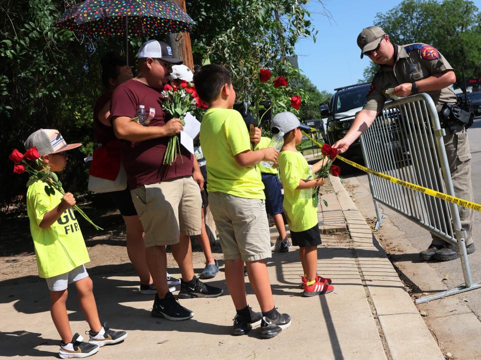 Public official hands out stickers to children at a memorial for Uvalde school shooting