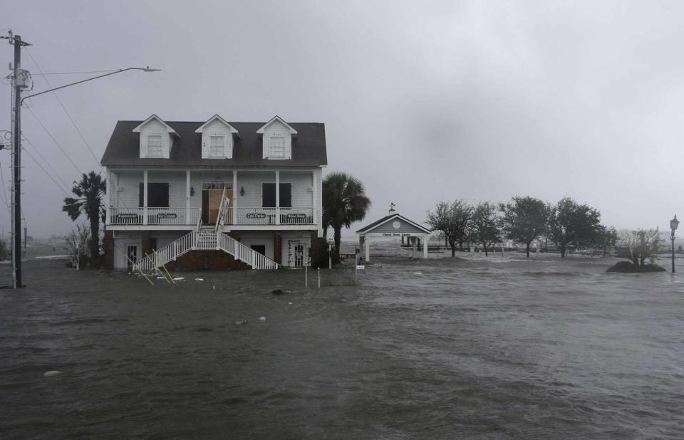 FILE - In this Sept. 14, 2018, file photo, high winds and water surround a house as Hurricane Florence hits Swansboro N.C. Historic coastal cities in the Southeast U.S. have survived disease outbreaks, wars and hurricanes over the past three centuries. Now they are trying to figure how to survive rising seas from climate change. (AP Photo/Tom Copeland, File)