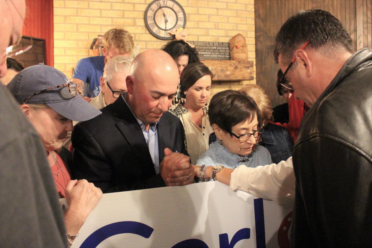 Carl Tepper, center, prays with friends and family including his wife Robyn, left, and state Sen. Charles Perry, right, after learning that he won the Texas House District 84 runoff Tuesday night.