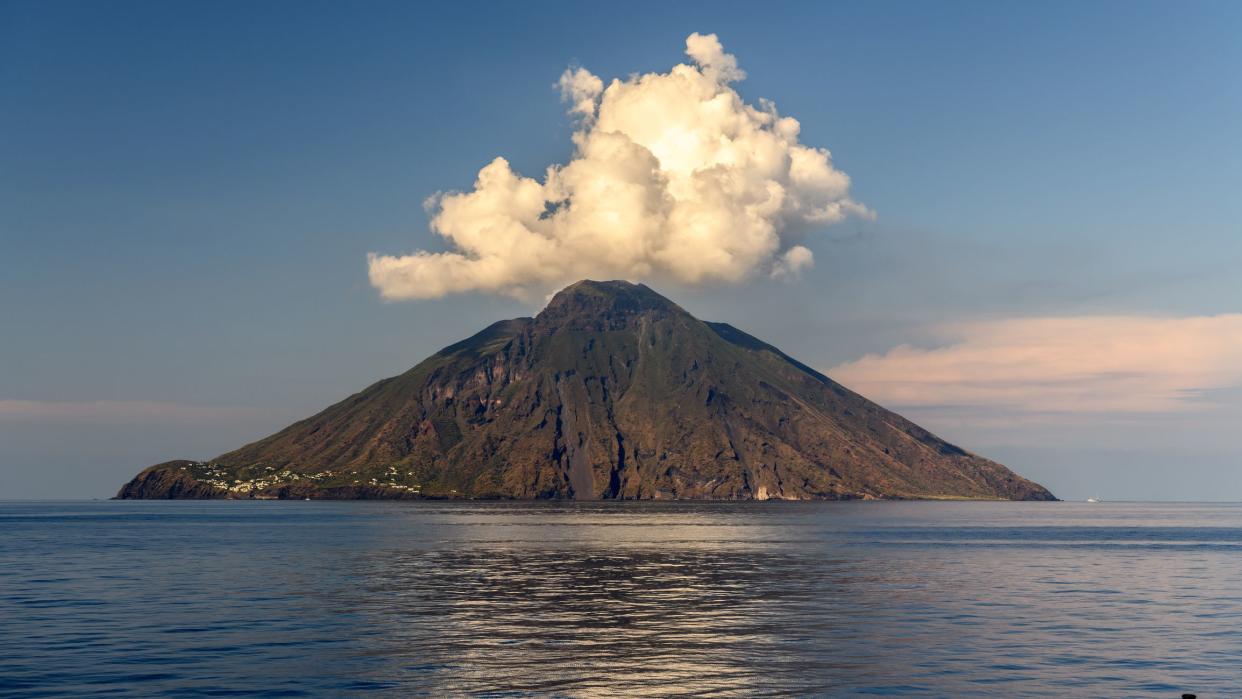 view of a smoking Stromboli volcano at sunset